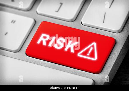 Pulsante rosso con la parola rischio e segnale di avvertimento sulla tastiera del computer, primo piano Foto Stock