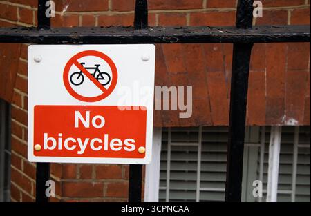 Primo piano di un cartello rosso di divieto “No Bicycles” fissato alle ringhiere metalliche di Londra. Foto Stock