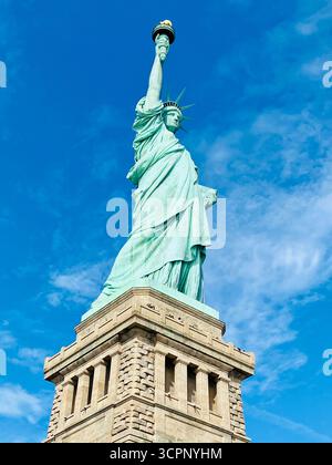 Statua della libertà vista da dietro con alberi d'autunno e cielo blu Foto Stock