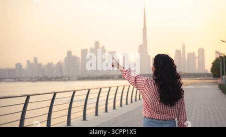 Sfondo immobiliare a Dubai con donna che punta verso lo skyline, con spazio per le copie, carta da parati poster 4k Foto Stock