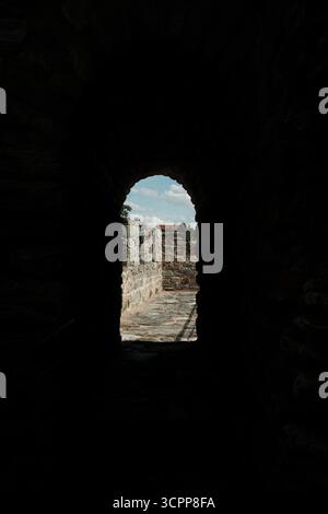 La luce del sole entra attraverso un passaggio ad arco in pietra presso la Fortezza RAM, rivelando un sentiero lungo il muro difensivo. Una popolare destinazione turistica. Foto Stock