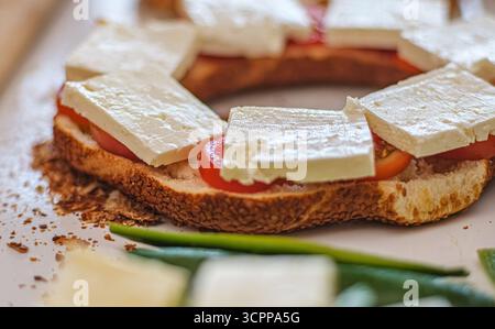 Un delizioso panino a vista con pomodori freschi e formaggio bianco cremoso. Perfetto per temi legati al cibo. Messa a fuoco selettiva. Foto Stock