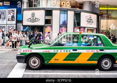 TOKYO, GIAPPONE - 27 OTTOBRE 2024 - immagine orizzontale di taxi verdi vicino al Tokyu Plaza Harajuku 'HARAKADO', un edificio dall'architettura moderna a Tokyo Foto Stock