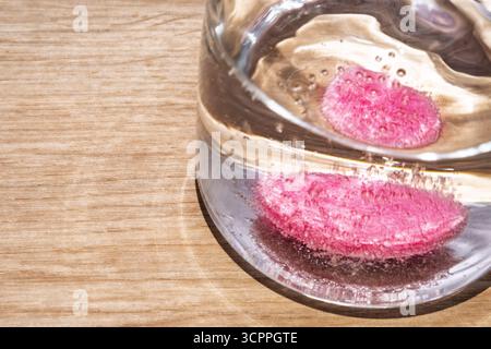 Compressa effervescente in un bicchiere d'acqua. Una compressa effervescente che si scioglie in un bicchiere d'acqua trasparente, circondata da bolle. Idea di idratazione. Foto Stock
