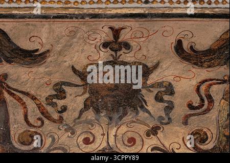 Corni di ariete dorati e lunghe orecchie appuntite: Il volto del fauno con gli occhi fissi è un ottimo esempio di grottesche manieriste tardo rinascimentali nel primo cortile o cortile di Michelozzo di Palazzo Vecchio, antico municipio in Piazza della Signoria, Firenze, Toscana, Italia. Gli affreschi sulle pareti del cortile includono creature mitiche, uccelli e fiori. Foto Stock