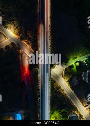 Vista aerea di strisce di luce che dipingono le strade buie mentre i veicoli attraversano il paesaggio sotto il soffice bagliore delle luci delle strade, la Canea, la Canea, la Grecia. Foto Stock