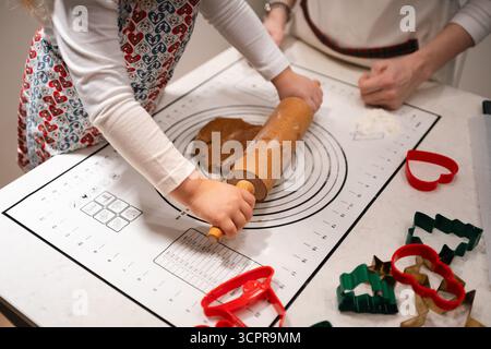 Un momento di gioia durante la cottura di deliziosi biscotti con un mattarello e delle creative taglierine per biscotti Foto Stock