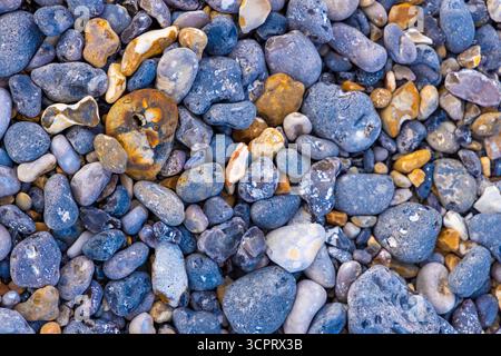 Ciottoli di vari colori e dimensioni si trovano sparsi su una spiaggia, creando un motivo vibrante sotto la luce del sole. Foto Stock