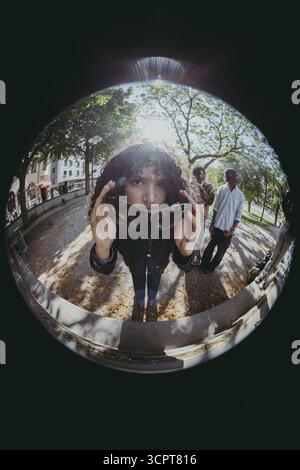 Fish Eye Lens ritratto di giovane donna sicura di sé che indossa occhiali da sole Foto Stock