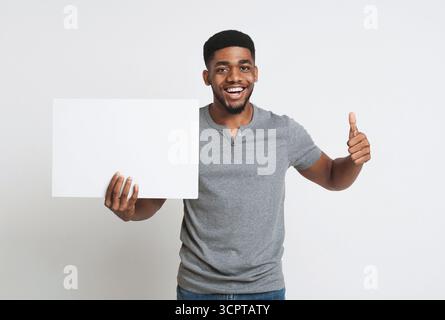 Uomo afro-americano che tiene una lavagna bianca e mostra il pollice in su Foto Stock