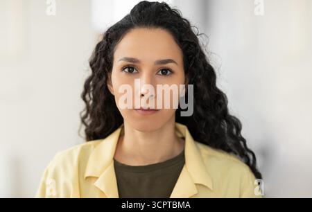 Ritratto di focalizzata giovane donna latina in abiti casual guardando la macchina fotografica a casa Foto Stock
