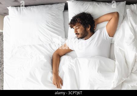 Vista dall'alto di un ragazzo indiano che dorme da solo a letto Foto Stock