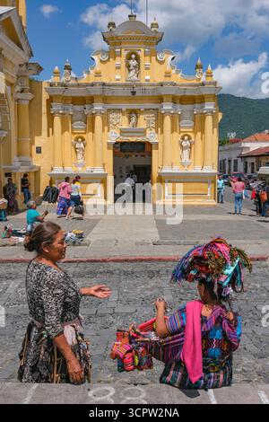 Antigua Guatemala, Guatemala - 12 agosto 2025: Donne in abbigliamento tradizionale di fronte alla chiesa di Santo Hermano Pedro de San Jose Betancur ad Antigua. Foto Stock