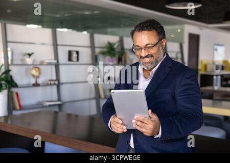 L'uomo d'affari guarda un tablet con un'espressione gioiosa Foto Stock