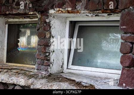 Una robusta parete in mattoni caratterizzata da una finestra bianca immacolata adornata da una cornice bianca e pulita che ne esalta l'aspetto complessivo Foto Stock