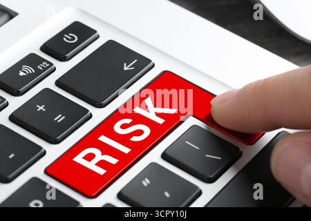 Donna che preme il tasto rosso con la parola rischio sulla tastiera, primo piano Foto Stock