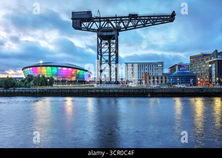 Il lungomare del fiume Clyde con la storica Finieston Crane, LA OVO Hydro Event Hall alcuni sviluppi moderni a Glasgow, Scozia, Regno Unito di notte Foto Stock
