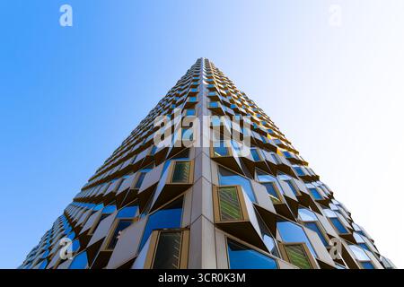 Moderno edificio residenziale con finestre a bovindo geometriche e vetro blu riflettente che creano una struttura architettonica dinamica Foto Stock