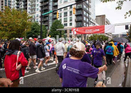I partecipanti all'American Heart Association 2025 Greater Charlotte Heart Walk si dirigono per le strade di Charlotte, North Carolina, sotto la pioggia leggera. Foto Stock