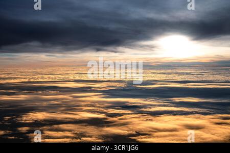 La luce del sole si irrompe attraverso strati di nuvole in volo Foto Stock