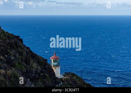 Una vista mozzafiato del faro di Makapu'u sulla costa orientale di Oahu, dove la ricca storia marittima delle Hawaii incontra le incontaminate scogliere oceaniche e l'oceano blu profondo Foto Stock