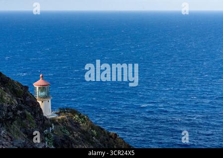Una vista mozzafiato del faro di Makapu'u sulla costa orientale di Oahu, dove la ricca storia marittima delle Hawaii incontra le incontaminate scogliere oceaniche e l'oceano blu profondo Foto Stock