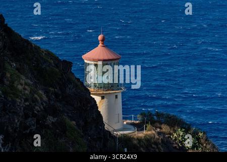 Una vista mozzafiato del faro di Makapu'u sulla costa orientale di Oahu, dove la ricca storia marittima delle Hawaii incontra le incontaminate scogliere oceaniche e l'oceano blu profondo Foto Stock