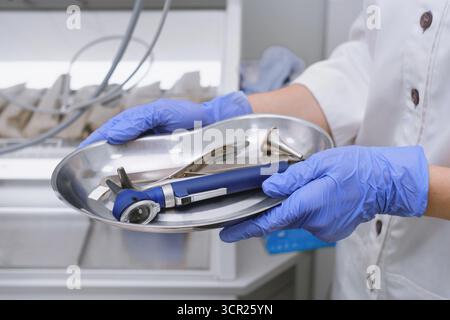 Primo piano di strumenti otorinolaringoiatrici in metallo su un vassoio medico in clinica. Strumenti otorinolaringoiatrici per esame di orecchio, naso e gola e procedure nelle mani Foto Stock