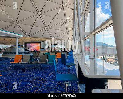 Hong Kong, Cina - 13 settembre 2025: Spaziosa e moderna area d'attesa dell'Aeroporto Internazionale di Hong Kong. Posti a sedere vivaci, soffitto geometrico e grande Foto Stock
