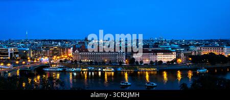 Paesaggio urbano di Praga al tramonto con skyline illuminato e riflessioni sul fiume. Questa immagine cattura il fascino architettonico e la vibrante atmosfera del Cze Foto Stock