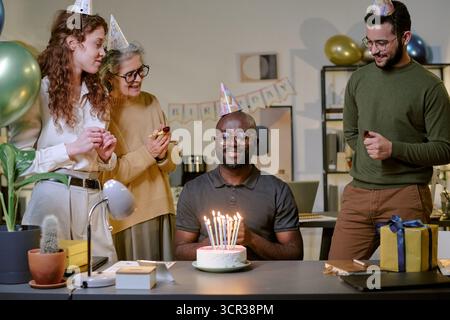 Black Man di mezza età sorride mentre festeggia il compleanno con gli amici Foto Stock