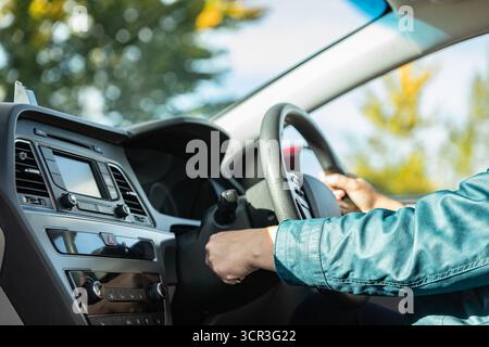 Donna che gira la chiave di accensione nella vettura con guida a destra. La mano di una donna avvia un'auto con la chiave. Abitacolo cruscotto auto. Una giovane donna che inizia a fare il m Foto Stock