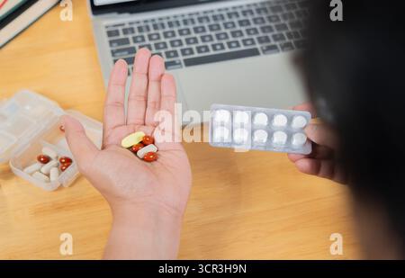 Concetto di sindrome da ufficio assumendo farmaci con attenzione selettiva. Un uomo, un impiegato, che tiene le pillole in mano. Ripresa retrovisiva. Foto Stock