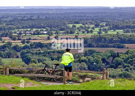 Un ciclista solitario che si gode la vista dalla cima di Box Hill Dorking Surrey Inghilterra Regno Unito Foto Stock