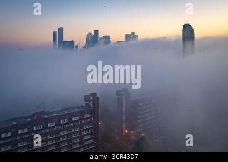 Londra, Regno Unito. 29 settembre 2025. Meteo nel Regno Unito: Edifici di Canary Wharf visti sopra la fitta nebbia della coperta mattutina mentre copre la maggior parte della città. Il Met Office emise un avviso giallo di nebbia quando le nuvole si muovevano in gran parte dell'Inghilterra orientale durante la notte, con una visibilità che scendeva a 50 metri in alcuni punti. Crediti: Guy Corbishley/Alamy Live News Foto Stock