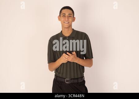 Il giovane è in piedi con un leggero sorriso, con le mani agganciate davanti a lui. Foto Stock