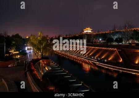 Illuminata dalle antiche mura della città e dai fossati che riflettono le luci di notte con cielo limpido. XI'an, Cina Foto Stock