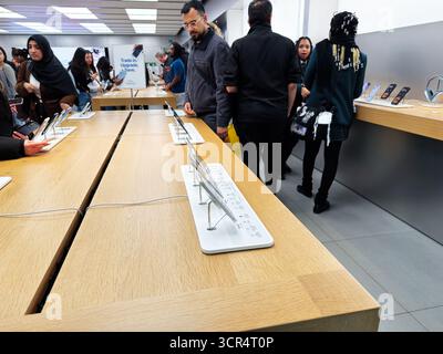 Manchester, Regno Unito - 26 settembre 2025: Le persone esplorano tablet e dispositivi in un vivace Apple store di elettronica con display luminosi Foto Stock