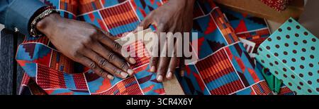 Intestazione di Black Woman che avvolge la confezione regalo con carta fantasia per celebrare Kwanzaa Foto Stock