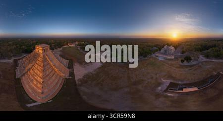 Vista aerea dell'iconica piramide di El Castillo immersa nel caldo bagliore del sole che tramonta, gettando ombre attraverso gli antichi terreni, Chichén Itzá, Yucatán, Messico. Foto Stock