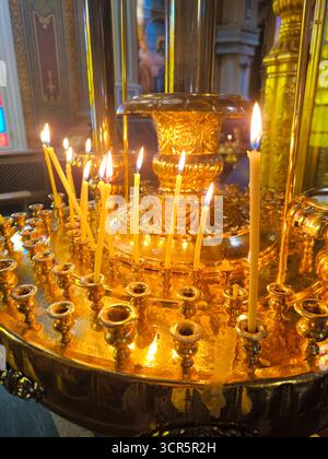 Un candelabro multilivello in metallo dorato, su cui bruciano le candele di cera. La luce soffusa della fiamma crea una calda atmosfera mistica. Il Foto Stock