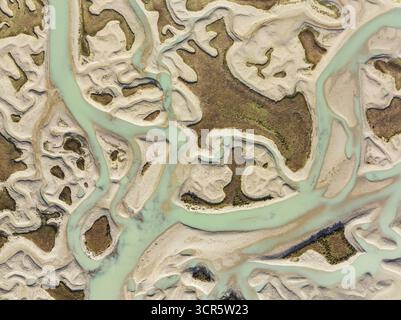 Vista aerea dei tortuosi corsi d'acqua intagliano intricati motivi attraverso le distese sabbiose, creando un arazzo di turchese contro il beige, Baia di Cádiz, Foto Stock