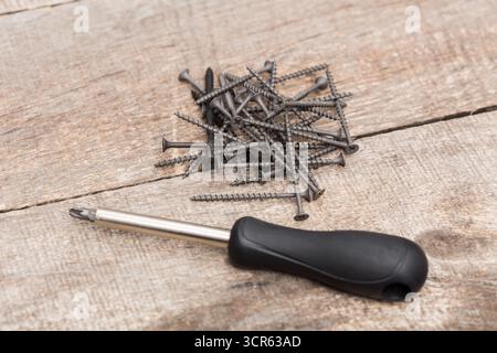 Utensili e viti sparsi su una superficie in legno per un progetto di miglioramento della casa Foto Stock