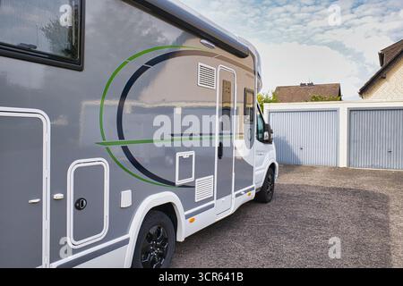 Moderno camper parcheggiato in una zona residenziale con garage sotto il cielo blu Foto Stock