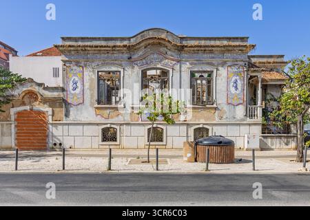 Una decadente casa portoghese classica a Setúbal, decorata con tradizionali piastrelle blu e bianche (azulejos), con finestre rotte e piante sovrastate. Foto Stock