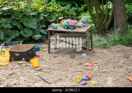 Giocattoli di plastica colorati sparsi in una sandbox esterna nel giardino estivo Foto Stock