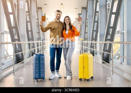 Coppia felice in aeroporto con passaporto e valigie, pronta per il viaggio Foto Stock
