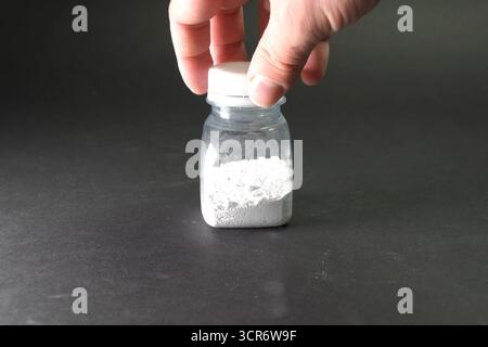 Polvere bianca in un vaso trasparente. Polvere bianca sul tavolo. Foto Stock