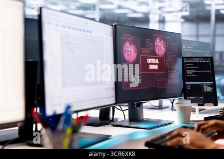 Amministratore di sistema nella server farm che combatte gli hacker che gestiscono il passaggio del firewall e rubano dati. Lavoratore che riceve una notifica di errore critico sul display del PC nello spazio di lavoro del data center Foto Stock
