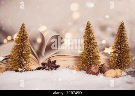Alberi di Natale fatti di filo e libro aperto con pagine piegate come un cuore nella decorazione natalizia Foto Stock